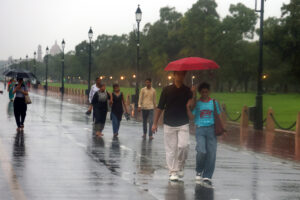 New Delhi: People walk with umbrellas